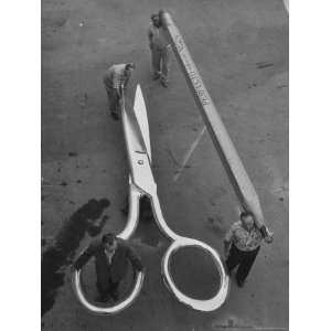 Stagehands Pushing a Pair of Gigantic Scissors on a Dollie Next to Two 